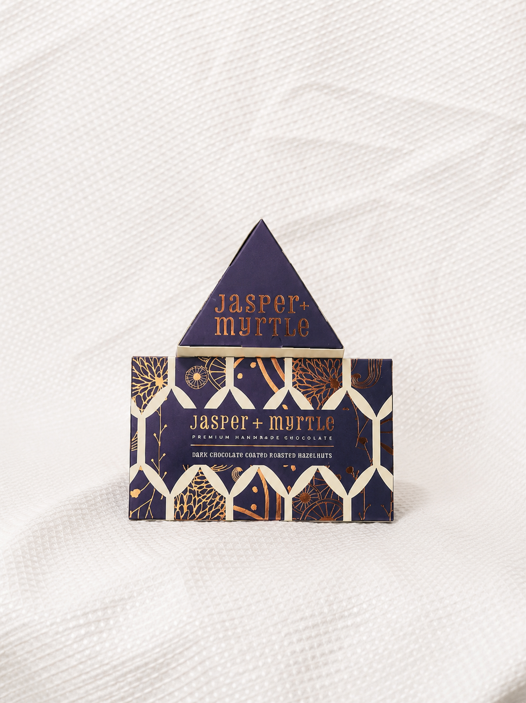 Two Jasper + Myrtle dark chocolate hazelnut gift boxes in triangular packaging, stacked together as a premium gourmet add-on from Rosella Florist Canberra.