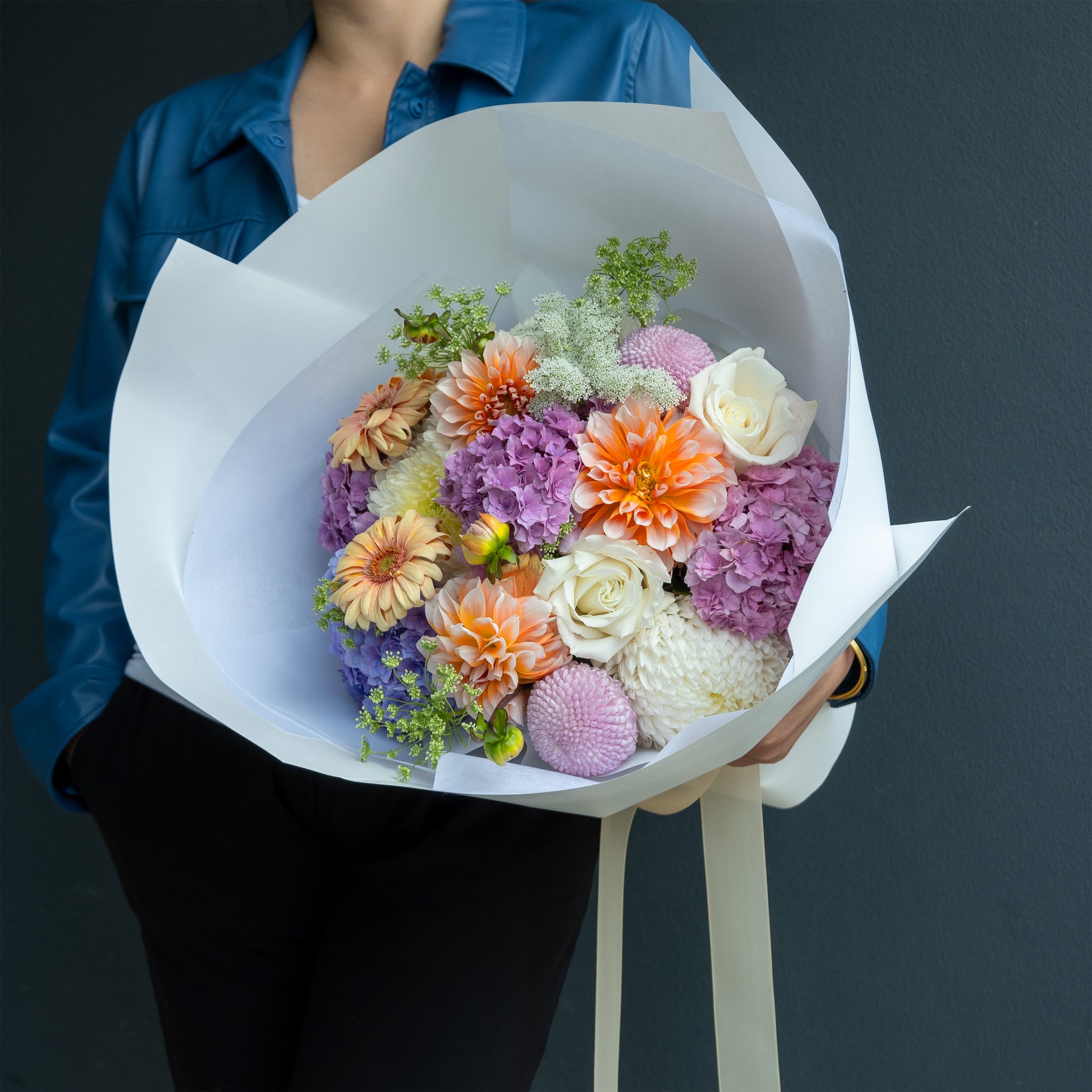 Bouquet of colorful flowers held by a person against a dark background