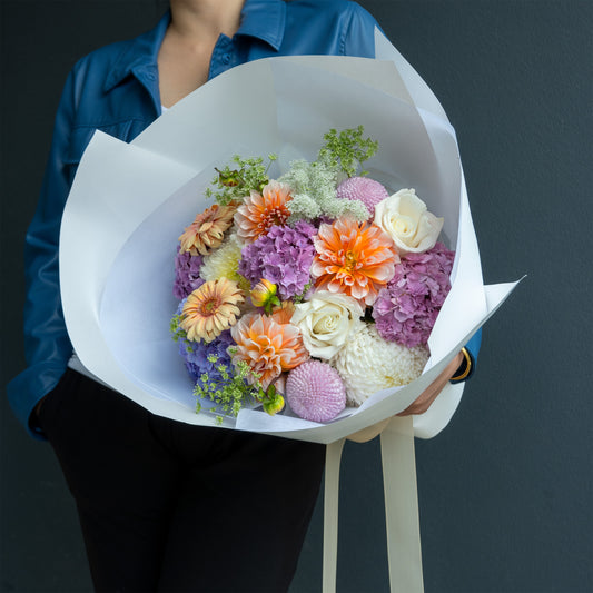 Bouquet of colorful flowers held by a person against a dark background